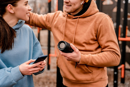 Young attractive sport woman and man in sportswear with wireless speaker listen to music at sports...