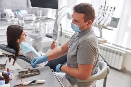 Cheerful positive dentist and client in dentistry. Female client sit in chairの写真素材