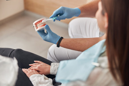 Dentist consultation - patient visit at dental clinics office. Male dentist explain about brushing...