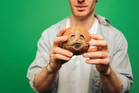 Close up man holds coconut, isolated on green backgroundの写真素材