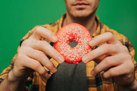 Man holds donut, isolated on green backgroundの写真素材