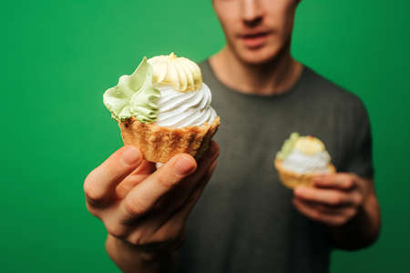 Close up young man holds deserts, isolated on green backgroundの写真素材