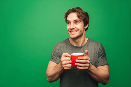 Man is drinking an instant coffee, isolated on green backgroundの写真素材