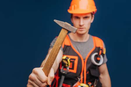 Close up builder in a helmet with a hammer, isolated over blue backgroundの写真素材