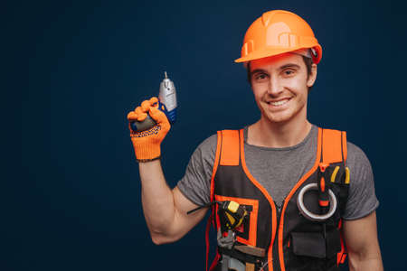 Attractive builder is having equipment in arm, isolated over blue backgroundの写真素材