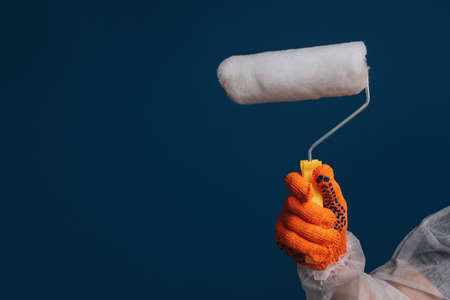 Builders hand is holding paint roller, isolated over blue backgroundの写真素材