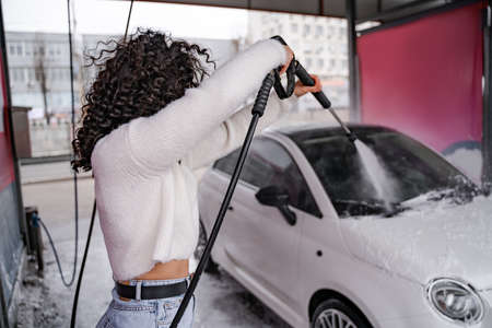 Girl wash personal auto on self-service car washの写真素材