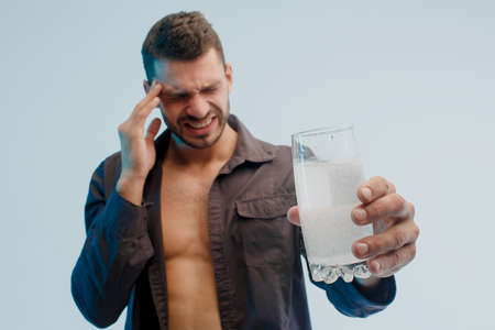 Man with headache hold glass with pill dissolvingの写真素材
