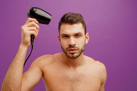 European man dry his hair with hairdryerの写真素材