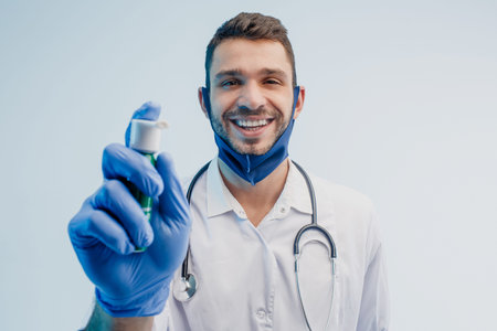 Smiling male doctor showing inhaler in studio