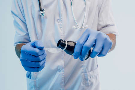 Male doctor pouring syrup from bottle to spoonの写真素材