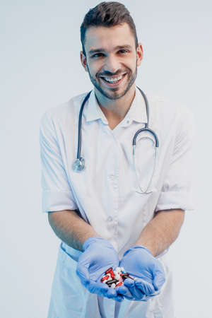 Smiling european male doctor showing medical pillsの写真素材
