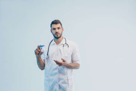 Serious european male doctor showing test jarの写真素材