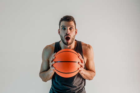 Surprised sportsman hold basketball ball in studioの写真素材