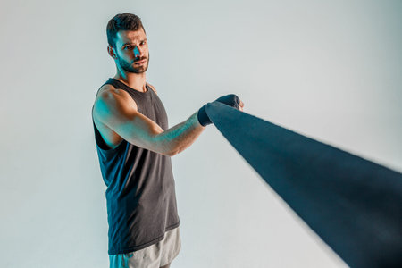 Sportsman wrapping boxing bandage on arm in studio