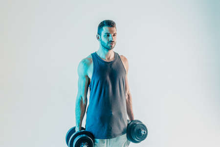 Serious sportsman holding a dumbbells in studioの写真素材