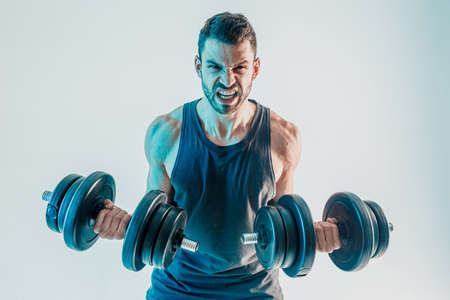 Young man training biceps muscles with dumbbellsの写真素材