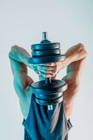 Young man training triceps muscles with dumbbellの写真素材
