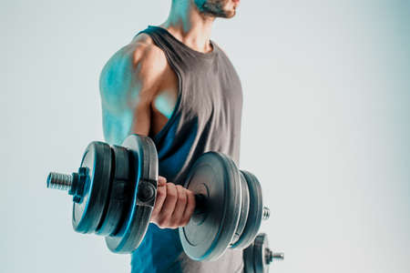 Young man training biceps muscles with dumbbellsの写真素材