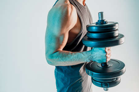 Young man training biceps muscles with dumbbellの写真素材