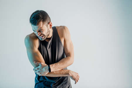 Exhausted young sportsman feeling pain in elbowの写真素材
