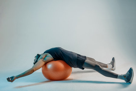 Sportsman lying on fitness ball after trainingの写真素材