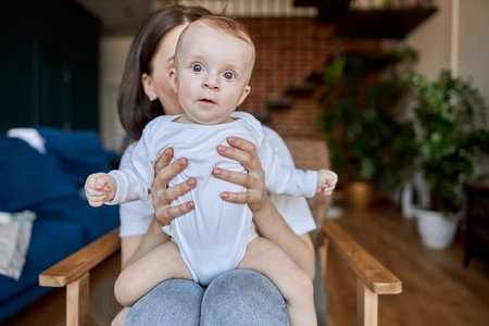Mother sitting and holding newborn baby in chair