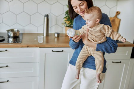 Mother holding bottle with milk for newborn babyの写真素材