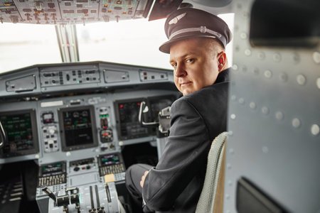 Male pilot in cockpit of passenger airplane jet. Modern plane with dashboard and air navigation....