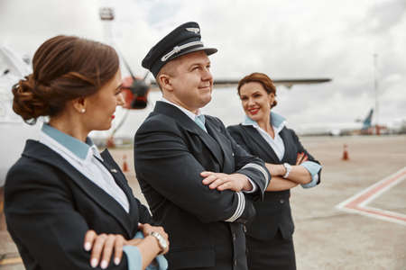 Pilot and stewardesses on runway near airplane jetの写真素材