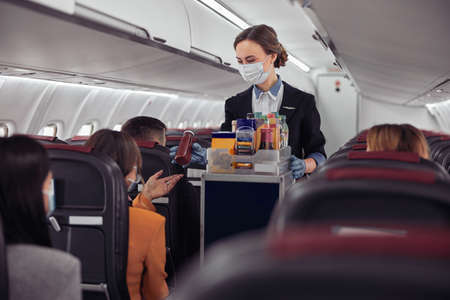 Stewardess giving bottle with drink to passengerの写真素材
