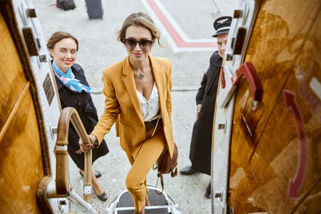 Businesswoman going up on ladder of airplaneの写真素材