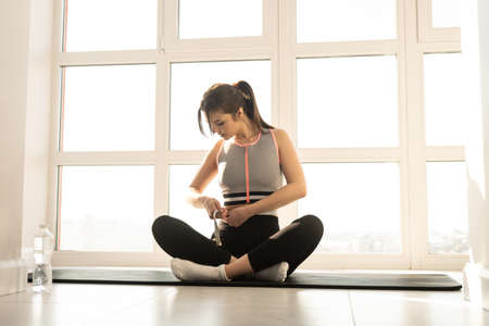 Sports woman measuring figure with measuring tapeの写真素材