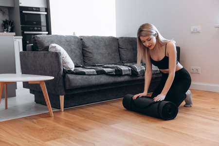 European woman collecting fitness mat at homeの写真素材