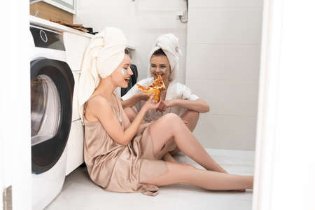 Young european women eating pizza in bathroomの写真素材