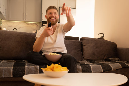 Laughing man sit on sofa and watch TV or movieの写真素材