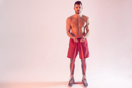 Young sportsman do exercise with resistance band