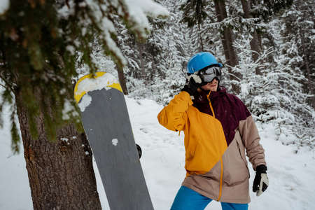 Winter sport and recreation, leisure outdoor activities. Man in ski equipment, wearing safety glasses. Snowboarder man hiking at mountainの写真素材