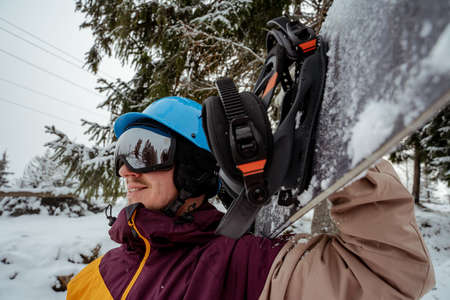 Man in ski equipment, wearing safety glasses. Adventure to winter sport. Snowboarder man hiking at mountain. Looking for powder to freerideの写真素材