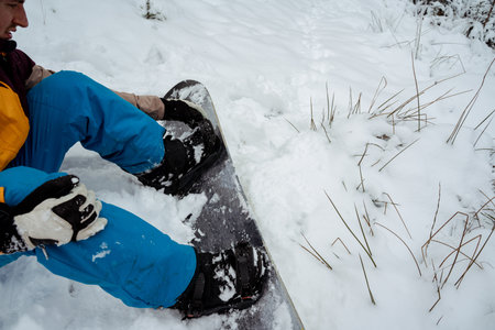 Snowboarder sitting alone in the snow, mountain outdoor, winter sport activity.の写真素材