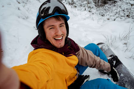 Adventure to winter sport. Snowboarder man hiking at mountain and making selfie. Looking for powder to freerideの写真素材
