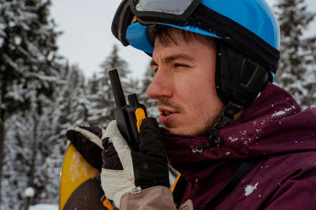 Man in ski equipment, wearing safety glasses, speaking on walkie-talkie. Looking for powder to freerideの写真素材