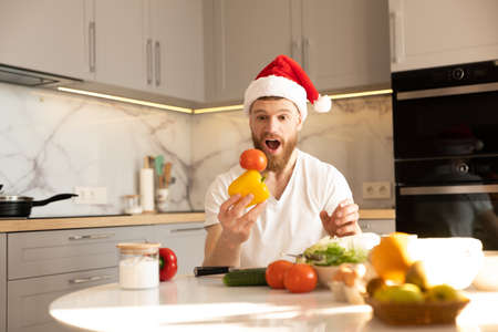 Man holding tomato on pepper at table on kitchenの写真素材