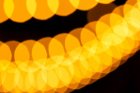 Soft overlapping yellow bokeh circles forming glowing, abstract light patterns against dark...