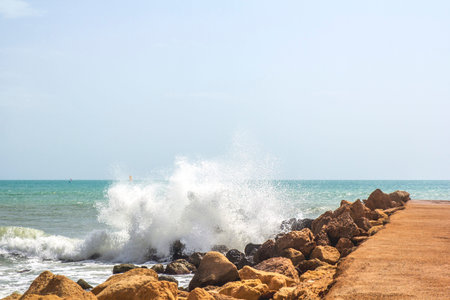 Mediterranean landscape. Coastal stones, sea view. Waves crash on the pier with splashes. Spain,...