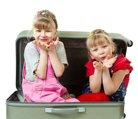 Two cute girls playing with a suircase isolated in white backgroundの写真素材