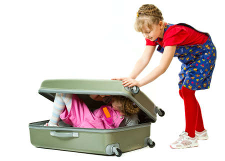 Two cute girls playing with a suircase isolated in white backgroundの写真素材