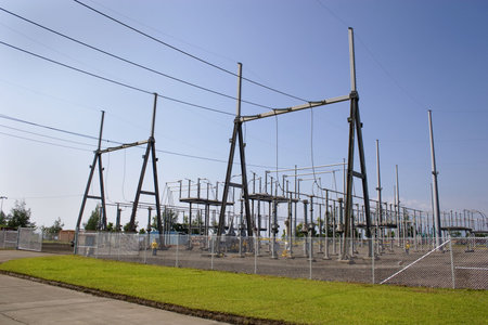 Switch yard maintenance works at a power facility with blue sky and green grass