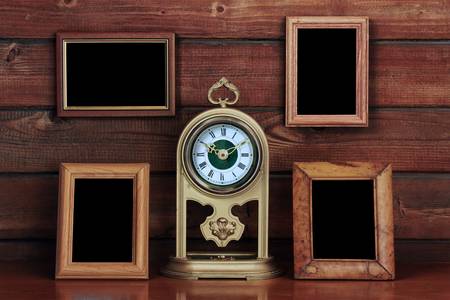 old photo frames and antique clock on wooden tableの写真素材
