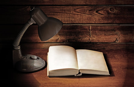 lamp and opened book on wooden table